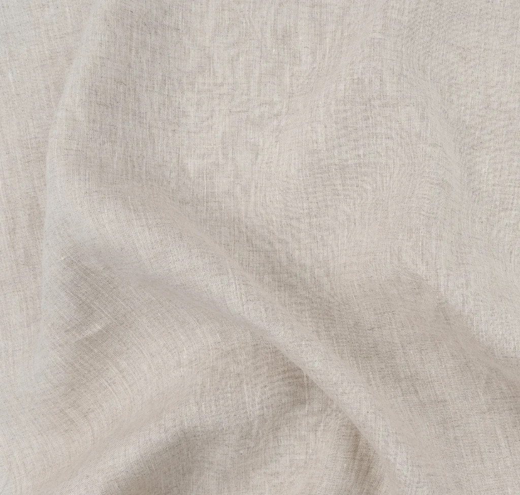 Close-up of light natural linen cloth showing its woven texture and drape.