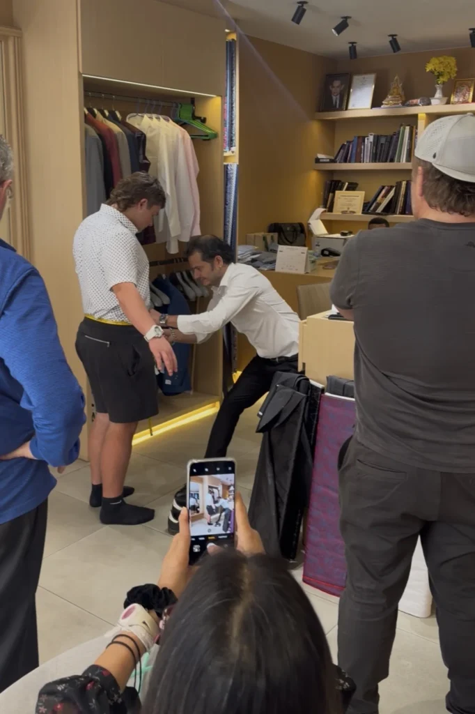 Tailor measuring the waist of a client for trousers