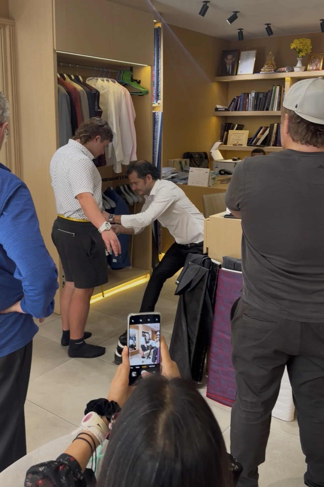 Tailor measuring the waist of a client for trousers