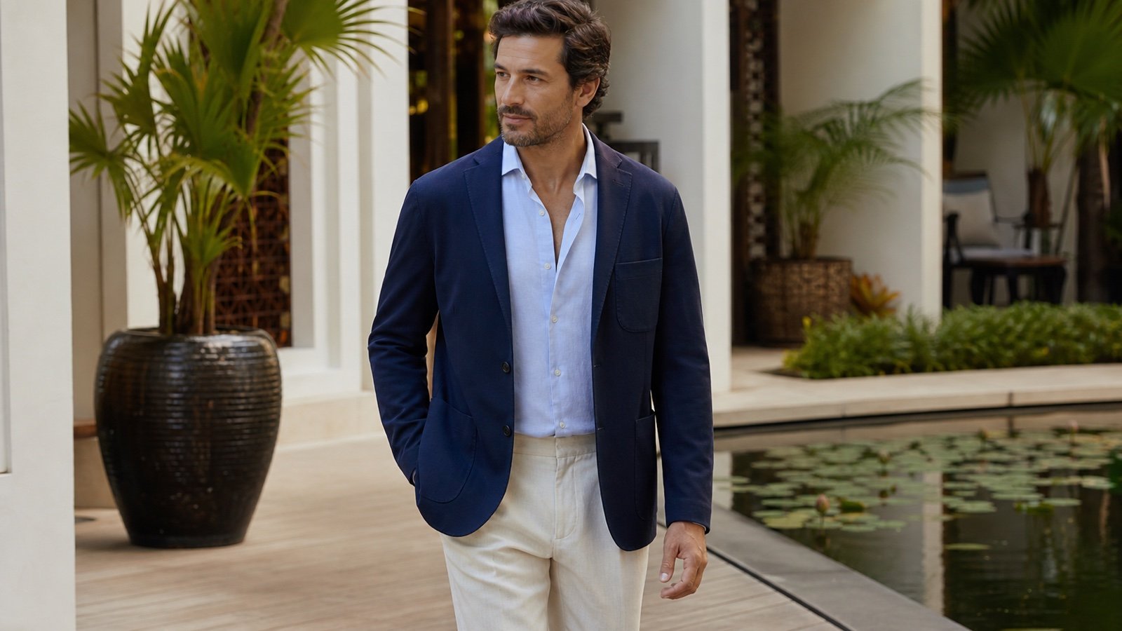 Fictional man wearing a navy patch-pocket jacket with an open-collar shirt in a generic courtyard